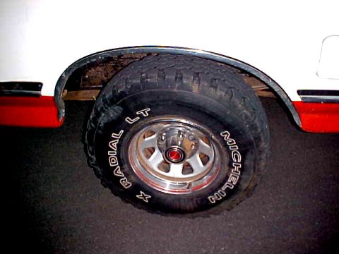 1987 Ford Bronco - A close-up view of a vehicle's wheel and tire, Michelin Radial X LT tires and a two-tone red and white fender flare.