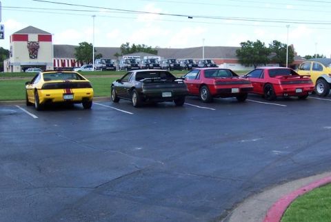 1988 Pontiac Fiero - A yellow 1988 Pontiac Fiero is parked in a lot with other Fieros.