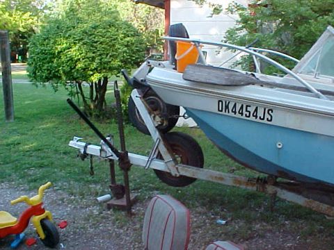 1987 Ford Bronco - A boat is seen on a trailer in a grassy area, with a license plate visible on the hull.