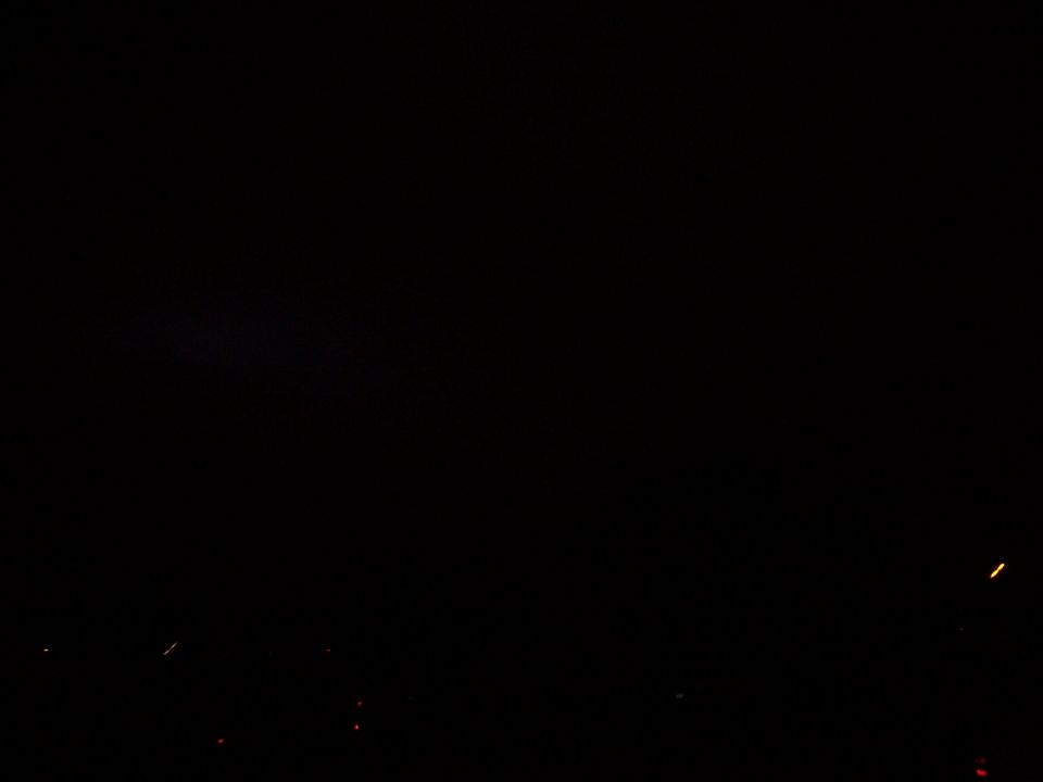Dark scene with scattered distant lights, possibly from a city or vehicles