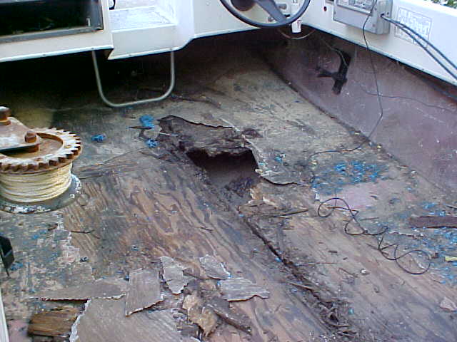 Interior of a boat with a damaged wooden floor and a winch
