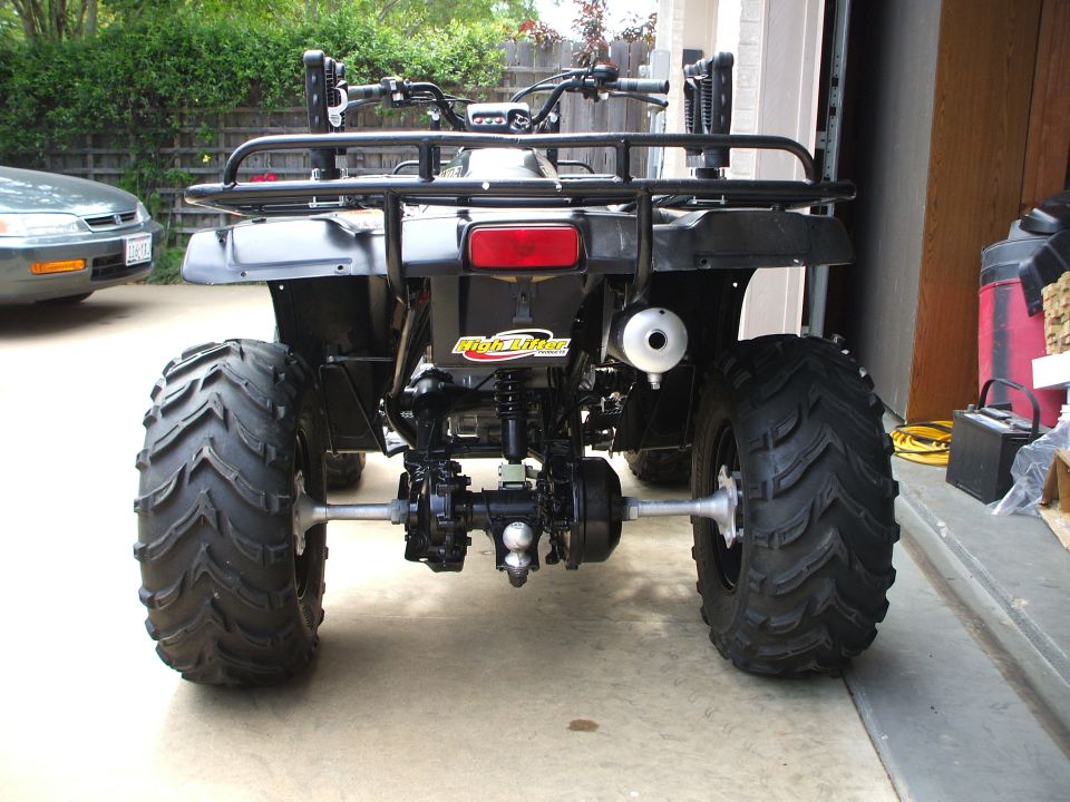 Rear view of black Honda FourTrax ATV with mud tires in a garage doorway