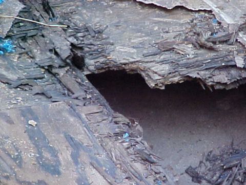 1987 Ford Bronco - A close-up view of a heavily damaged vehicle body, revealing layers of material and debris.