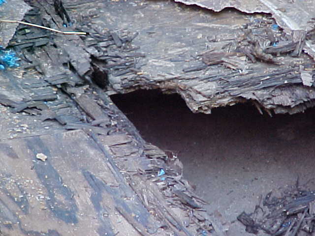 Damaged dark blue vehicle body with exposed layers and debris, close-up