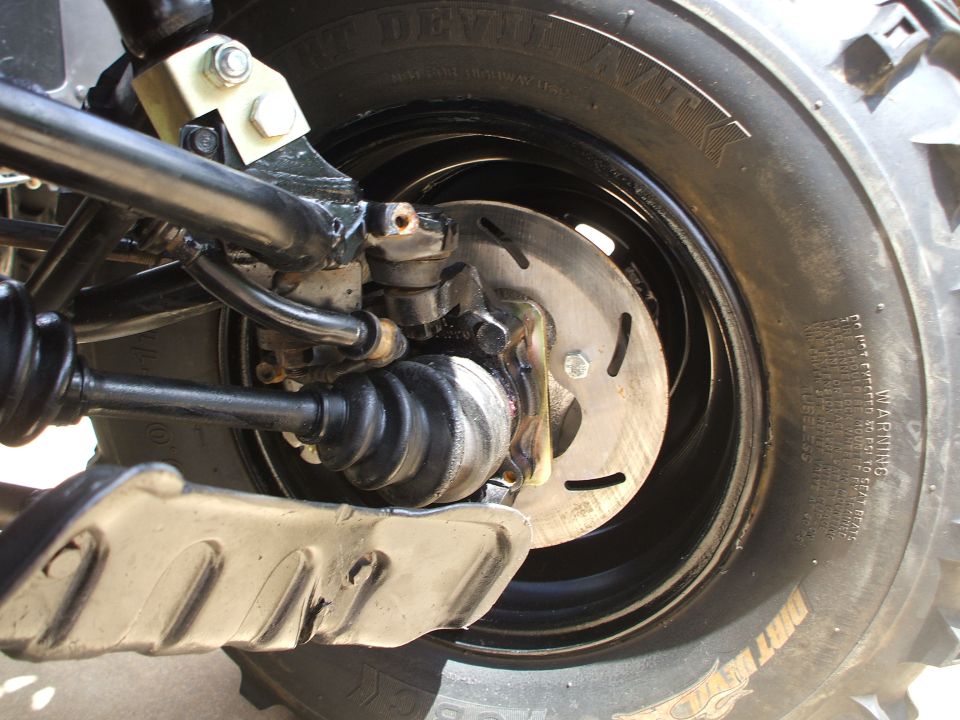ATV brake rotor, CV boot, A-arm and knobby tire close-up