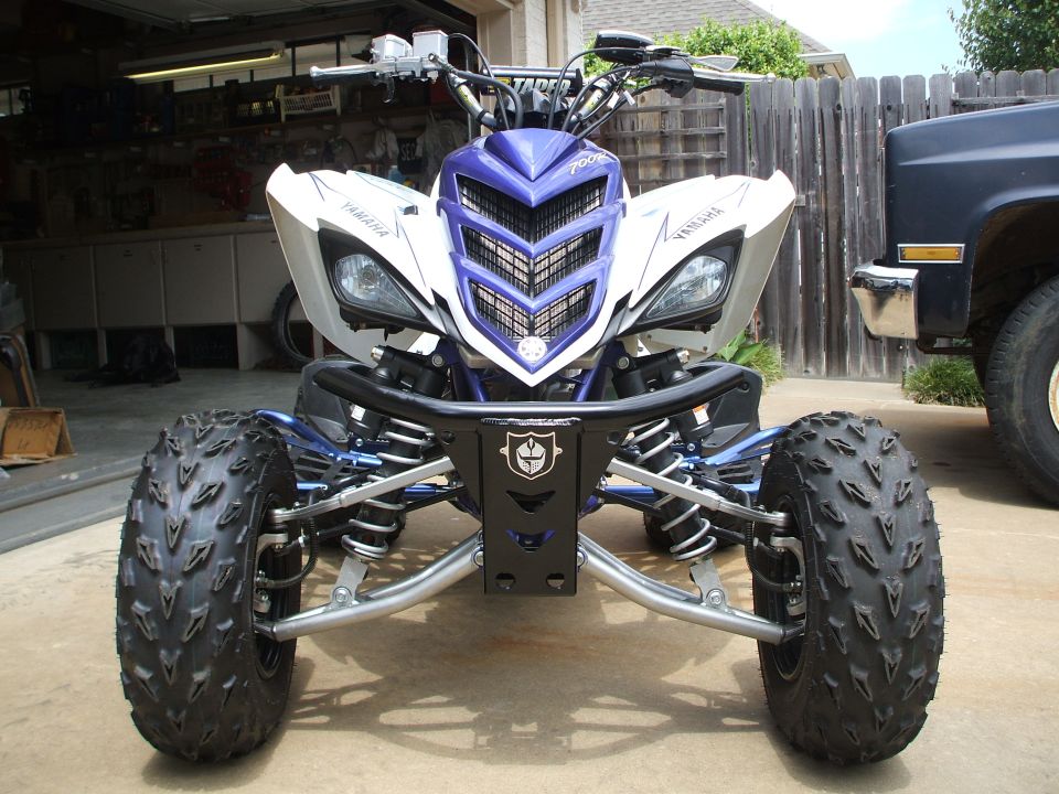 Blue and white Yamaha Raptor ATV, front view, on driveway by garage
