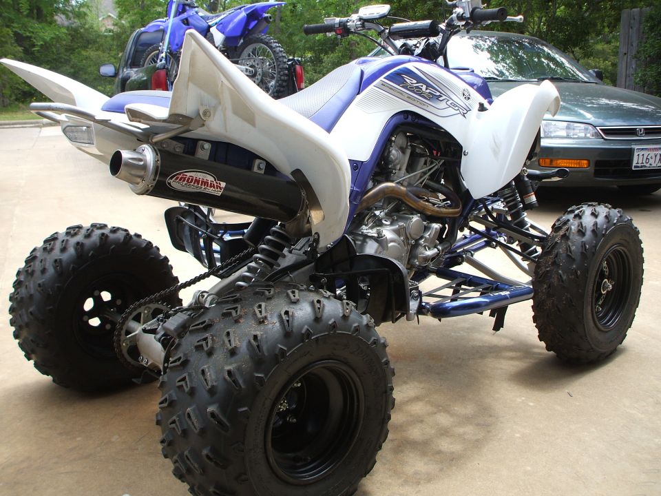 White and blue Yamaha Raptor ATV rear three-quarter view on driveway