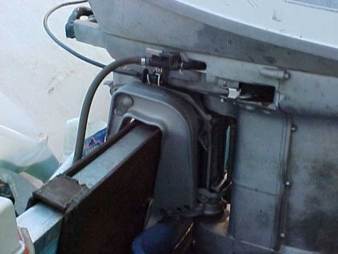 1987 Ford Bronco - Detail of an outboard motor's mounting bracket and control cables, showing mechanical components.