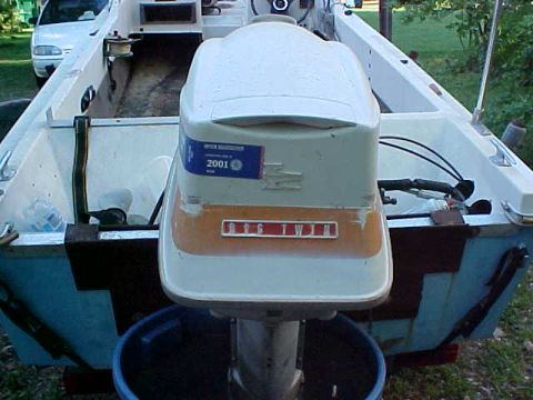 1987 Ford Bronco - A boat motor is mounted on the back of a boat, with another vehicle visible in the background.
