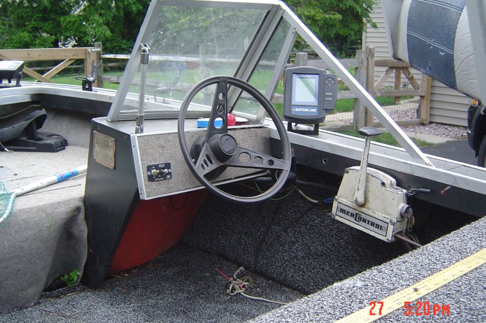 Boat interior showing steering wheel, dashboard, and seats
