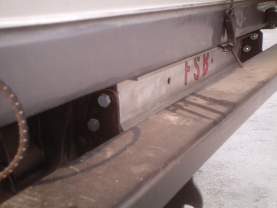 Close-up of a metal bracket with red text 'FSB' on a vehicle frame