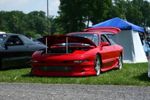 1994 Ford Probe - A red sports car is displayed with its hood and trunk open at an outdoor event.