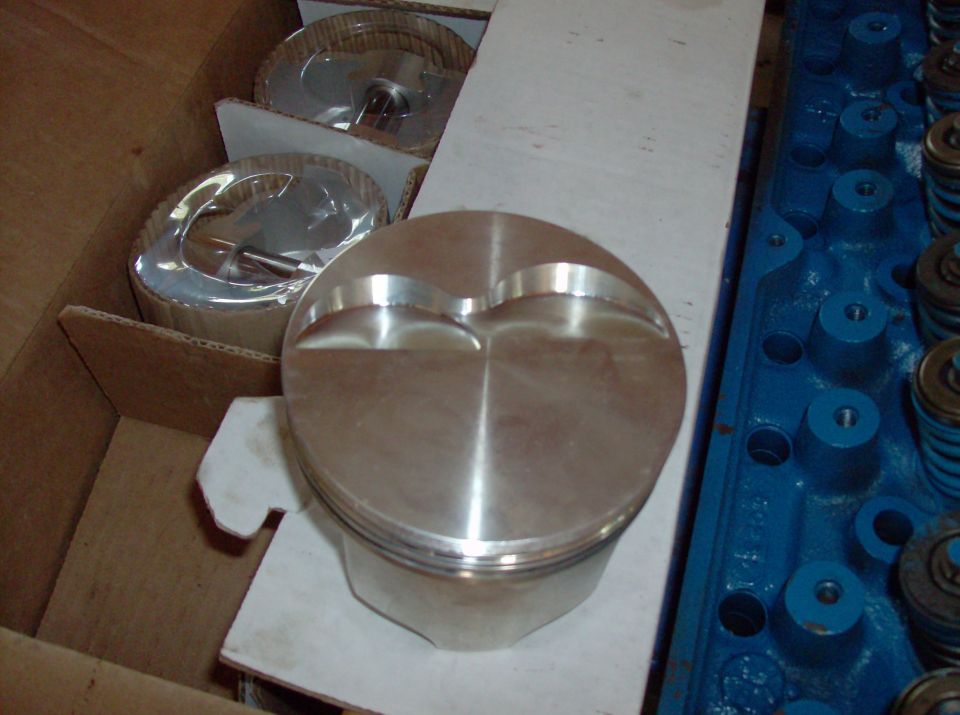 Close-up of a new dished aluminum piston in a cardboard box