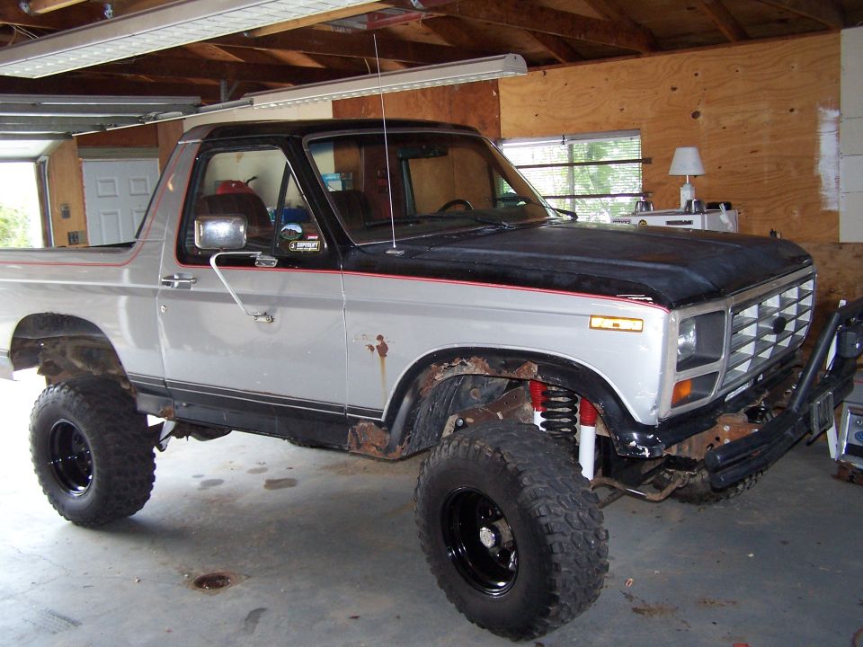 Silver and black lifted Ford Bronco with aftermarket wheels and off-road suspension