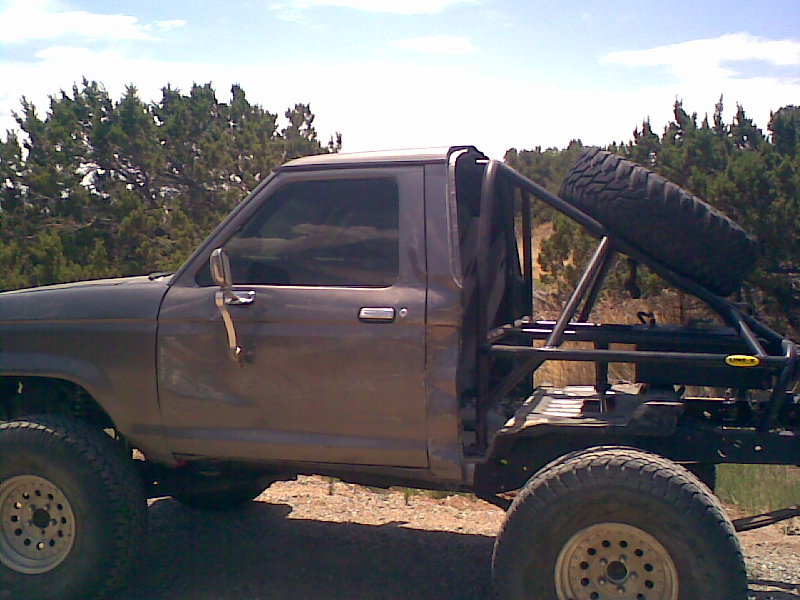 side view of a lifted pickup truck with a roll cage and spare tire mounted in the bed
