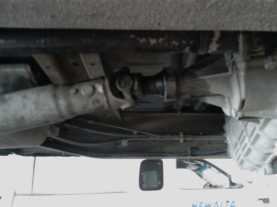 Underside view of a vehicle's driveshaft connected to the transmission