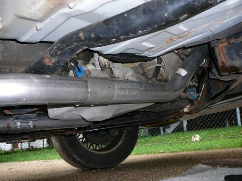 1997 Mercury Grand Marquis - Close-up view of the exhaust system components, including a shiny stainless steel pipe and a blue electrical connector.