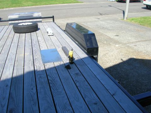 1996 Ford Bronco - Trailer deck shows a spare tire, metal plate, and tools including a grinder.
