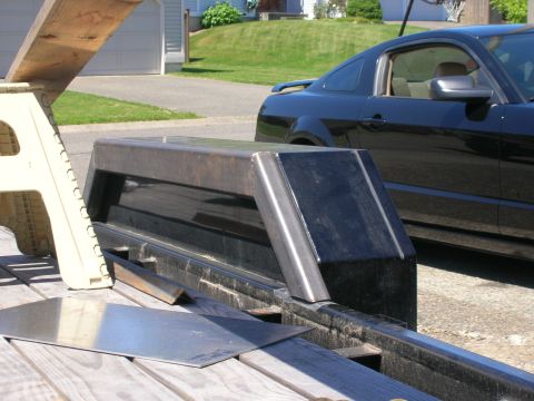 1996 Ford Bronco - A custom metal piece is being fabricated on a trailer, with a black car parked nearby.