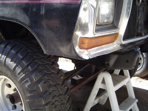 1979 Ford Bronco - Front view of a black Ford truck with a large tire and lifted suspension, showing the fender and turn signal.