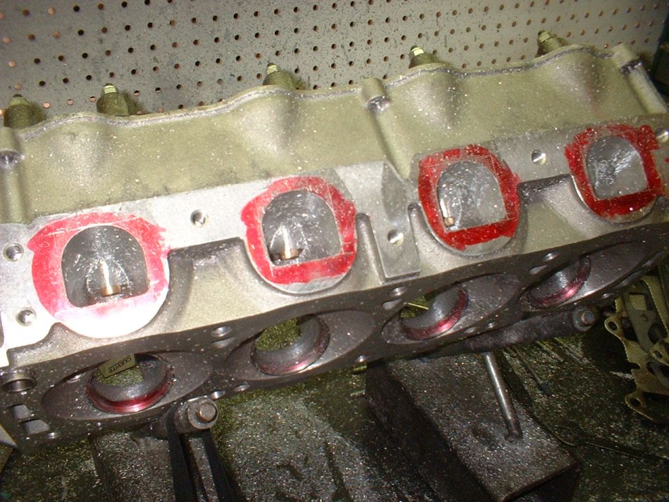 V8 cylinder head with red layout dye around intake ports during porting work on a shop bench