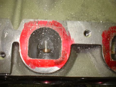 1965 Shelby Cobra - Close-up view of an engine cylinder head port, showing red sealant around the opening and a brass valve guide within.