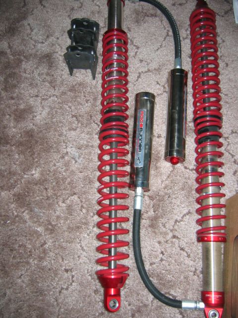 1992 Ford Mustang - Two red coilover suspension shocks and a remote reservoir are laid out on a carpeted surface.