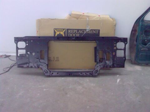 1996 Ford Bronco - A metal radiator support is shown in front of a cardboard box labeled "REPLACEMENT DOOR".