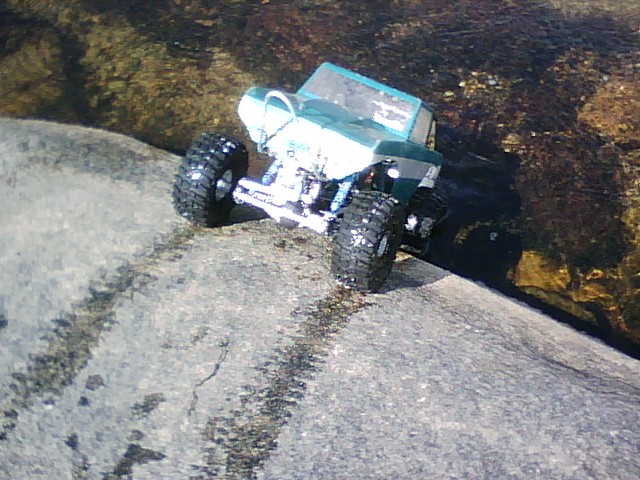 Toy off-road vehicle with large tires on a rock near water