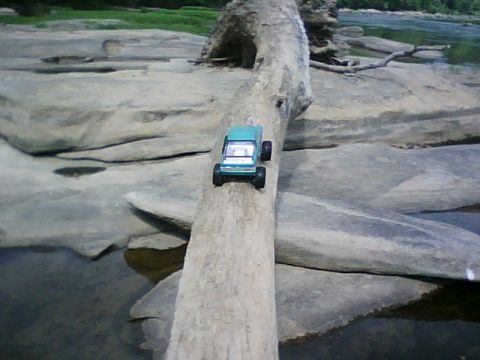 1996 Ford Bronco - Toy truck balanced on a log over a rocky stream.