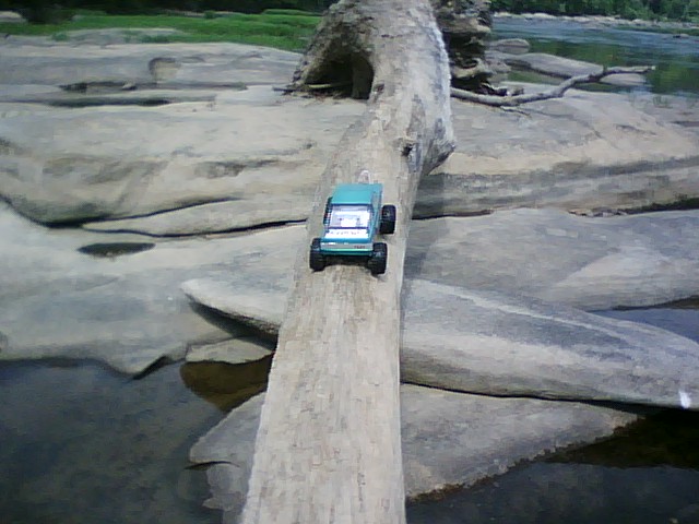 Toy truck on a log across a rocky stream bed