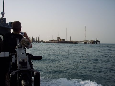 1981 Kenworth W900A - A person on a military boat photographs offshore oil rigs in the distance.