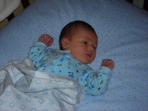 1984 Ford Bronco - A newborn baby rests comfortably in a crib, swaddled in a blanket with a star pattern.