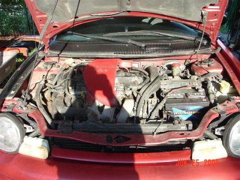 1997 Dodge Neon - The engine bay of a red 1997 Dodge Neon is visible with the hood open.