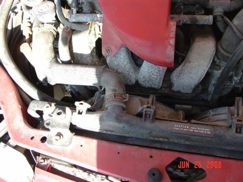 1997 Dodge Neon - Close-up of an engine bay with radiator and hoses visible. Text on radiator warns about the rear window.