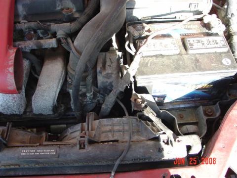 1997 Dodge Neon - The engine bay of a vehicle, a battery and various hoses and components.