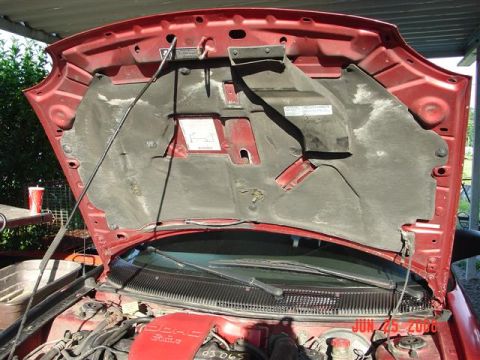1997 Dodge Neon - The hood of a red vehicle is open, revealing the engine bay and sound-dampening material. A watermark indicates the photo was taken on June…