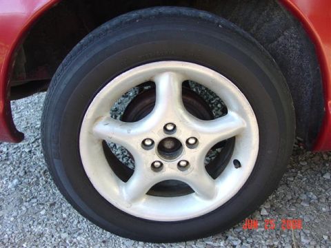 1997 Dodge Neon - Close-up of a red car's wheel and tire, a silver five-spoke rim.