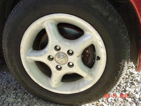 1997 Dodge Neon - Close-up of a car wheel and tire, showing the five-spoke design and center cap.