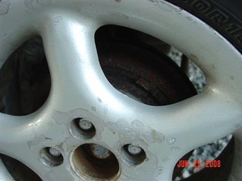 1997 Dodge Neon - Close-up of a corroded silver alloy wheel and tire, with a brake rotor visible.
