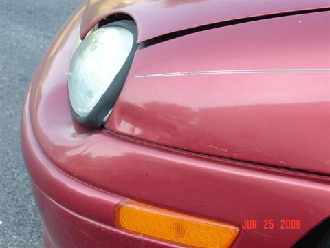 1997 Dodge Neon - Close-up of a red 1997 Dodge Neon's front corner, showing the headlight and turn signal.