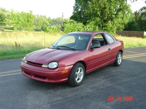 1997 Dodge Neon - A red 1997 Dodge Neon coupe is parked on asphalt with a grassy area and trees in the background.
