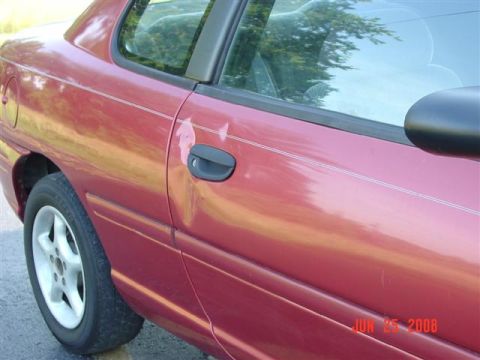 1997 Dodge Neon - A red sedan's side profile shows a dent on the door and a visible wheel, with a date stamp in the corner.