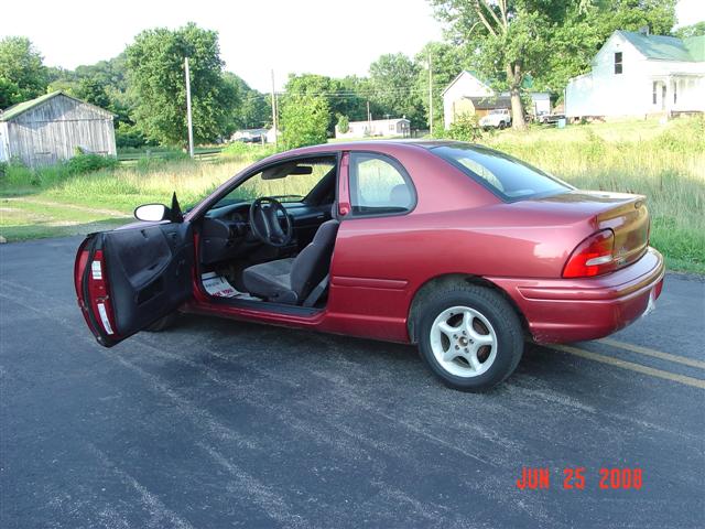 Red 1997 Dodge Neon coupe with driver's door open, parked on asphalt