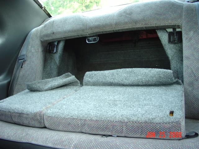 Back seat of a car with the bottom cushions folded up and the seat backs down, revealing the trunk area