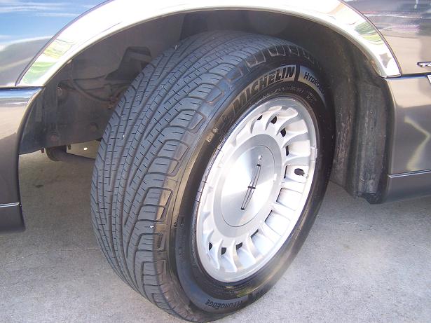 Close-up of Michelin HydroEdge tire on silver Lincoln alloy wheel of a dark gray sedan