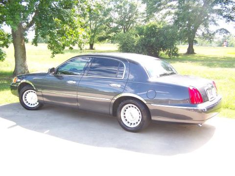 1998 Lincoln Town Car - Dark gray 1998 Lincoln Town Car seen from the side parked outdoors on a sunny day.