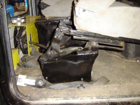 1992 Ford Bronco - Close-up of the seat mounting mechanism and floor matting inside a vehicle.