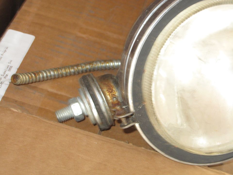 Close-up of a headlight assembly with a flexible metal conduit and mounting bolt