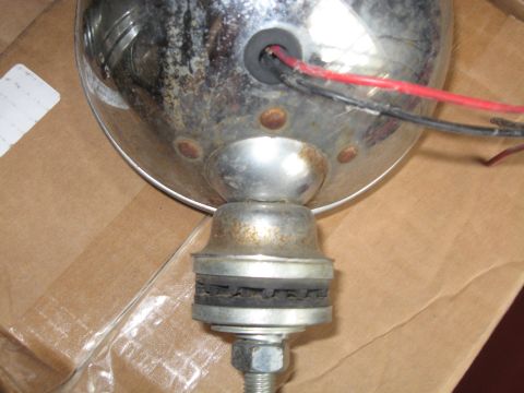 1990 Ford Bronco - A close-up view of a single chrome headlight, revealing its mounting hardware and electrical connections.